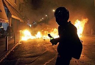 A protestor holds a molotov cocktail next to a burning barricade in Athens.(AFP/Louisa Gouliamaki)