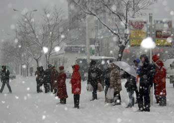 People wait for buses on a snow-covered road in Penglai of Yantai city, east China's Shandong Province, Dec. 21, 2008.(Xinhua Photo)