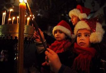Palestinian Christian children wear festive hats as they light candles inside the Church of Nativity, believed by many to be the birthplace of Jesus Christ, during Christmas celebrations in the West Bank town of Bethlehem, Wednesday, Dec. 24, 2008. [Agencies]
