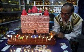 A shopkeeper places candles on the model of a cake resembling the "Taj Mahal" hotel which was damaged during the Mumbai attacks last month, in the north eastern city of Siliguri December 23, 2008. REUTERS/Rupak De Chowdhuri