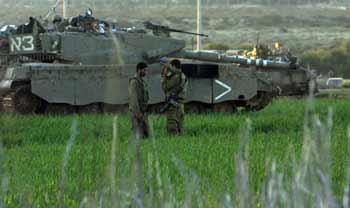 Two Israeli soldiers rest beside the tank in the Gaza Strip Jan.6, 2009. The Israeli army has said that it would hold fire in the Gaza Strip for three hours every day from Jan.7 to allow local residents to prepare basic supplies.(Xinhua/Tsafrir Abayov)