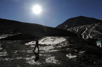 A foreign tourist walks along the Karola glacier, which situates at the boundary betweent the Nagarze county and the Gyangze county of southwest China's Tibet Autonomous Region, Jan. 14, 2009. The glacier tongue locates at an altitude of 5,560 meters, extending from the top to the roadside. (Xinhua/Jin Liangkuai)