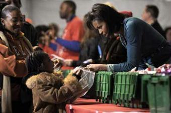 Michelle Obama (R), the wife of US President-elect Barack Obama, talks to a little girl as she celebrates National Day of Service by helping volunteers with 'Operation Gratitude and 'Serve DC' by assembling care packages for US troops overseas in Washington January 19, 2009.(Xinhua/Reuters Photo)