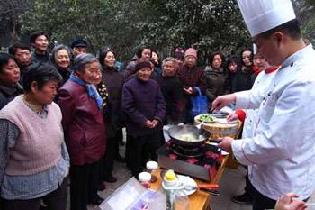 Community residents watch the culinary skill shown by a hotel's chef, who came to the July 1st Community to teach the residents refined cookery for the family reunion dinner on the Chinese lunar New Year's Eve, in Xuchang, central China's Henan Province, Jan. 20, 2009. (Xinhua/Niu Shupei)