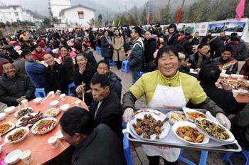 A woman serves with big smile on her face during a banquet to celebrate moving into new house in Dongjiaxinyuanzi town of Dujiangyan City, southwest China's Sichuan Province, Jan. 22, 2009. As their homestead was destroyed in the earthquake in May 2008, about 400 families in Dongjiaxinyuanzi town moved to new houses on Jan. 22. (Xinhua/Wang Jianhua)