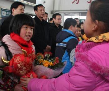 A girl from quake-affected Sichuan Province (L) receives a gift from her peer of "love family" at the railway station in Cangzhou, north China's Hebei Province, Jan. 22, 2009. Children from ten poor families of Pingwu county, Mianyang city, southwest China's Sichuan Province were invited by volunteer charity families in Cangzhou to spend the Chinese Lunar New Year, which falls on Jan. 26 this year. (Xinhua/Fu Xinchun) 