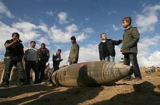 Palestinians look at an unexploded bomb dropped by the Israeli airforce in Rafah near the Gaza Strip's border with Egypt.(AFP/Said Khatib)