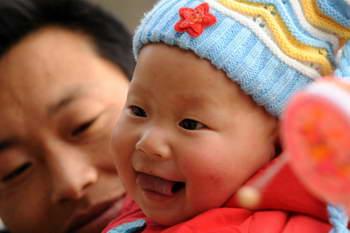 Baby Gao Zhen smiles in his father' s arms in Shuicaogou Village in Wenxian County of Longnan City, northwest China's Gansu Province, on Jan. 24, 2009. Gao Zhen with the nickname Zhensheng which means born on the day of the earthquake happened was dressed in new clothes to celebrate the coming Spring Festival. (Xinhua/Han Chuanhao)