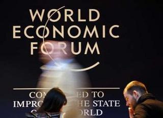People walk in front of a logo in the venue of the World Economic Forum (WEF) in Davos January 26, 2009.REUTERS/Denis Balibouse