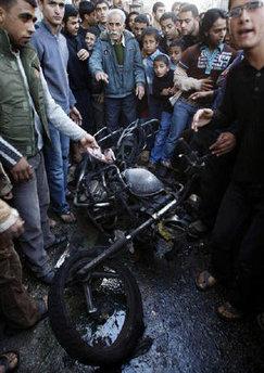 Palestinians look at a destroyed motorcycle after an Israeli air strike in Khan Younis in the southern Gaza Strip January 27, 2009.REUTERS/Ibraheem Abu Mustafa
