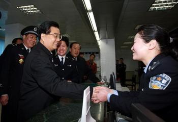 Chinese President Hu Jintao(L2) shakes hands with a policewoman on duty at the Kuaizixiang police station, Nanchang, East China's Jiangxi Province, January 26, 2009. [Xinhua]
