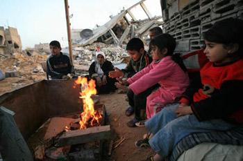Palestinians get warm by a fire in the rubbles in al Moghraqa area in the central Gaza Strip, Jan. 29, 2009. The reconstruction of Gaza Strip after a ceasefire is almost at a standstill due to the continuous blockage of Gaza by Israel and different opinions on receiving international aid in the Palestinian side. (Xinhua/Wissam Nassar) 