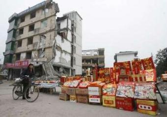 A vendor (R) sells goods for the upcoming Chinese New Year near a building damaged in the Sichuan earthquake in Dujiangyan, Sichuan province January 22, 2009. Chinese people all over the world will usher in the Lunar New Year on January 26. Picture taken January 22, 2009.REUTERS/Stringer