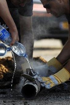 Israeli police sappers pour water to cool the remains of a rocket launched by Palestinian militants in the Gaza Strip that hit the southern city of Ashkelon on February 3.(AFP/David Buimovitch)