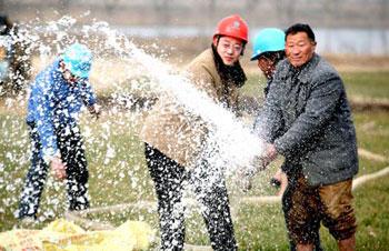 Workers of a power company help a farmer to irrigate the field in Wuhe County, east China's Anhui Province, Feb. 5, 2009. China raised the drought emergency class Thursday from level two to level one, the highest alert, in response to the worst drought to hit northern China in half a century, according to a State Council meeting. (Xinhua/Yan Ruipeng)