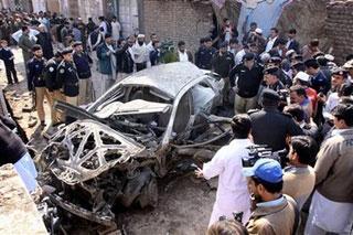 Pakistani police watch a destroyed car after an explosion in Peshawar, in northwest Pakistan, Wednesday, Feb. 11, 2009. (AP Photo/Mohammad Sajjad)