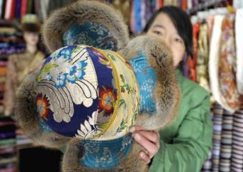 A shopowner shows a traditional hat of Tibetan ethnic group at her shop in Lhasa, capital of southwest China's Tibet Autonomous Region, on Feb. 18, 2009. Traditional clothes of Tibetan ethnic group are popular among people of Tibetan ethnic group as Tibetan New Year, which falls on Feb. 25 this year, is coming. (Xinhua/Purbu Zhaxi)