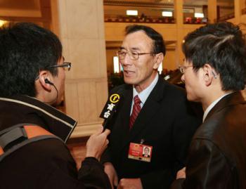 Qiangba Puncog (C), deputy to the Second Session of the 11th National People's Congress (NPC) from southwest China's Tibet Autonomous Region, receives interview prior to the third plenary meeting of the Second Session of the 11th NPC held at the Great Hall of the People in Beijing, capital of China, March 10, 2009.  (Xinhua Photo)