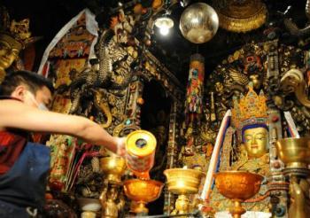 A Lama adds ghee to the lamp in front of the figures of Buddha in the Jokhang Temple in Lhasa, capital of southwest China's Tibet Autonomous Region, Mar. 11, 2009. A celebration for the ghee flowers and lanterns festival was held in the Jokhang Temple, attracting the visitors from all over the country. (Xinhua/Chogo)