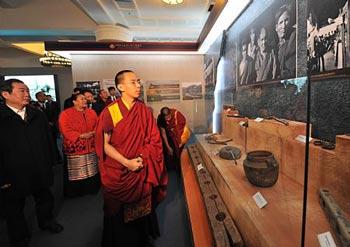 The 11th Panchen Lama Erdeni Gyaincain Norbu (front) looks at the exhibits during an exhibition titled "Democratic Reform in the Tibet Autonomous Region" in Beijing, capital of China, March 15, 2009. (Xinhua/Fan Rujun)
