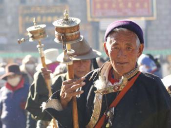 Buddhism followers of the Tibetan ethnic group spin their prayer wheels to spread spiritual blessings to all sentient beings and invoke good karma in their next life when walking on a street in Lhasa, capital of southwest China's Tibet Autonomous Region, in November 2007.(Xinhua/Soinam Norbu)