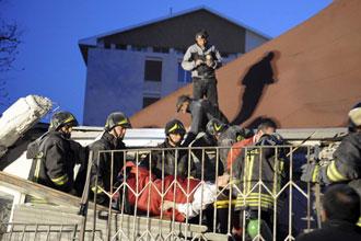 Rescue workers carry an injured woman away from her house in Aquila April 6, 2009. [Agencies]