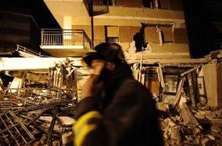 A rescuer walks past a collapsed building in L'aquila, Italy, earth April 7, 2009. The strong earthquake that hit central Italy on Monday has killed at least 179 people, injured some 1,500 and left around 70,000 homeless, Italian media reported on Tuesday.(Xinhua