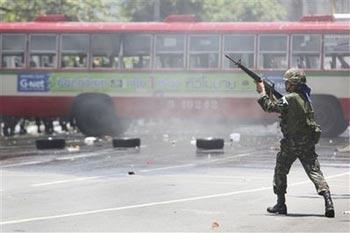 A Thai soldier fires a shot into the air as they clear anti-government protestors from the streets near downtown Monday, April 13, 2009, in Bangkok, Thailand. Thai authorities have declared a state of emergency shutting down rail service as soldiers continue to battle against anti-government demonstrators.(AP Photo/Wong Maye-E)