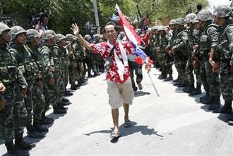 A Thai anti-government protester leaves Government House through a line of soldiers in Bangkok, Thailand, Tuesday, April 14, 2009. (AP Photo/Wong Maye-E)