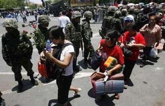 Supporters of ousted Thai prime minister Thaksin Shinawatra leave the Government House area as soldiers watch in Bangkok April 14, 2009.REUTERS/Kerek Wongsa