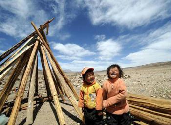 Two children play near the timber for house building at the quake-hit area of Yangyi Village, Geda Town, Damxung County of Lhasa, capital of southwest China's Tibet Autonomous Region, on April 20, 2009. (Xinhua Photo) 