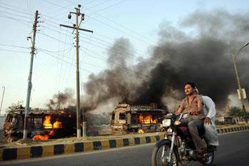 A Pakistani motorcyclist rides past a burning passenger mini bus on a street in Karachi.(Xinhua/Reuters Photo)