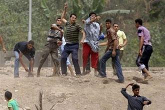 Egyptian youths throw rocks towards police during clashes over a mass cull of pigs in Cairo. Egyptian riot police clashed with stone-throwing pig farmers who were trying to prevent their animals being taken away for slaughter as part of a mass nationwide cull. (AFP/Khaled Desouki)