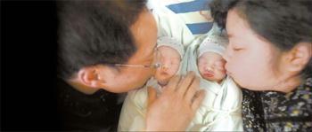 Zhao Yu and her husband kiss their twins Wang Bohua and Wang Boxiao, who were born on April 23, 2009. The couple, whose 10-year-old daughter Wang Ruoyu was killed in the May 12 earthquake in Sichuan province, said they now have new hope in life. [CFP]