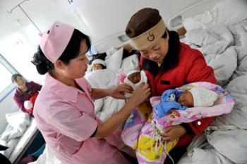 Zhang Hongmin (R) carries her newborn twins at a prefab hospital in Qingchuan, southwest China's Sichuan Province on Sunday, May 10, 2009. New lives never stop their steps to be born in the quake-devastated areas. So far more than 300 newborns have been born at the prefab hospital and these newborns, for those families in the quake-hit areas, are their "sunshine", igniting their hope to start a new life. Pregnant mothers, among whom are mothers who lost their children in the devastated Wenchuan Earthquake on May 12, 2008, are often seen nowadays in the prefabs and newly-built houses. When there are offspring, there is hope and future. The moment of new birth is endowed with significance as the one-year anniversary of the Wenchuan Earthquake approaches. [Photo: Xinhua/Li Ziheng/Cai Yang]