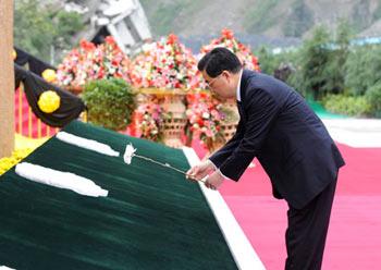 Chinese President Hu Jintao places a white chrysanthemum in front of a commemorative wall of the earthquake during the commemorative service to mark the first anniversary of May 12 Earthquake in Yingxiu Township of Wenchuan County, southwest China's Sichuan Province, May 12, 2009. (Xinhua/Li Xueren)