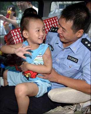 Lang Zheng (L), known as the "Salute Boy", leaves Tangdu Hospital in the arms of his father Lang Hongdong after two months of treatment, in Xi'an, capital of northwest China's Shaanxi Province, July 27, 2008. Lang, from the Qushan Township Kindergarten of Beichuan Qiang Autonomous County in southwest China's Sichuan Province, was rescued from the debris after the May 12 Wenchuan earthquake. After being put on a stretcher, the injured and fragile boy slowly raised his right hand and saluted his rescuers in gratitude. The moment was captured by a photographer and moved the whole nation. His fractured left arm and partly amputated left fingers have been recovering well during the two months at Tangdu Hospital.