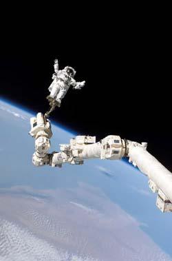 Astronaut Stephen K. Robinson, STS-114 mission specialist, anchored to a foot restraint on the International Space Station’s Canadarm2, participates in the mission’s third session of extravehicular activity (EVA). The blackness of space and Earth’s horizon form the backdrop for the image.