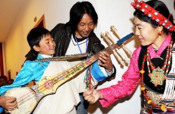 Rgyatso is learning how to play the guitar from his papa Tashi Wangla and mom Dawa, photo from Xinhua.