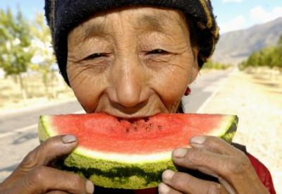 A villager has a taste of a piece of watermelon she planted in Xigaze, southwest China's Tibet Autonomous Region, on Sept. 17, 2009. Taking advantage of the sunshine in Xigaze, farmers have planted watermelons on a large scale here in recent years. (Xinhua/Purbu Zhaxi)