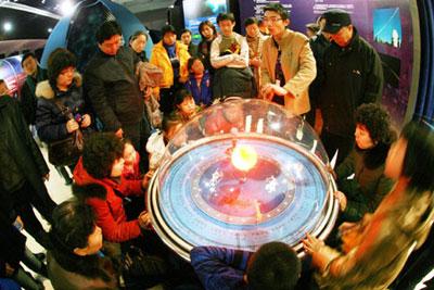 Visitors in loop around a celestial sphere listen to the illustration of solar and lunar eclipse, at the Beijing Planetarium, where wide varieties of activities are presented during the Spring Festival to lure more astronomic amatuers to go through the gamut of astronomy in Beijing, Jan. 30, 2009.(Xinhua/Chen Xiaogen)