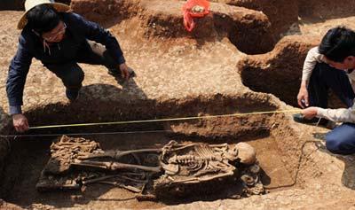 Jiang Zhilong (L), researcher of the Yunnan Provincial Cultural Relics Archeology Research institute, and head of the archeology team, measures the length of a skeleton in a grave in the Jinlian Mountains of Dengjiang County, southwest China's Yunnan Province, on March 12, 2009. The grave forest located in the Jinlian Mountains and covering an area of about 40,000 square meters, is confirmed as the largest scale grave forest in the bronze culture archeology history. Chinese archeologists had found more than 400 cultural relics including bronze wares, pottery, jade articles and ironwares since last October after the graves were found in 2006. The grave forest is considered as an important discovery with great values for researching the ancient culture in Yunnan province.(Xinhua)