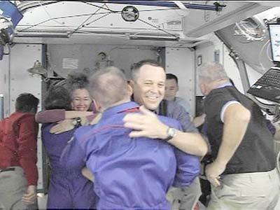 In this image from NASA Television, Wednesday, March 25, 2009, shuttle Discovery astronauts hug with international space station astronauts as they depart the ISS. Space shuttle Discovery has left the international space station. The shuttle undocked from the orbiting outpost Wednesday after eight days. Discovery and its crew of seven are due back Saturday. (Xinhua/AFP Photo)