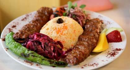 The adana kebab consists of two long rolls of ground lamb slipped off their skewers, white rice, and several vegetable sides.