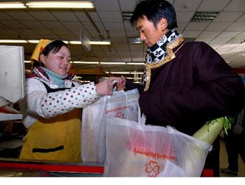 Pungcok gets free environment-friendly shopping bags in a supermarket, photo from Xinhua, January 10, 2008.